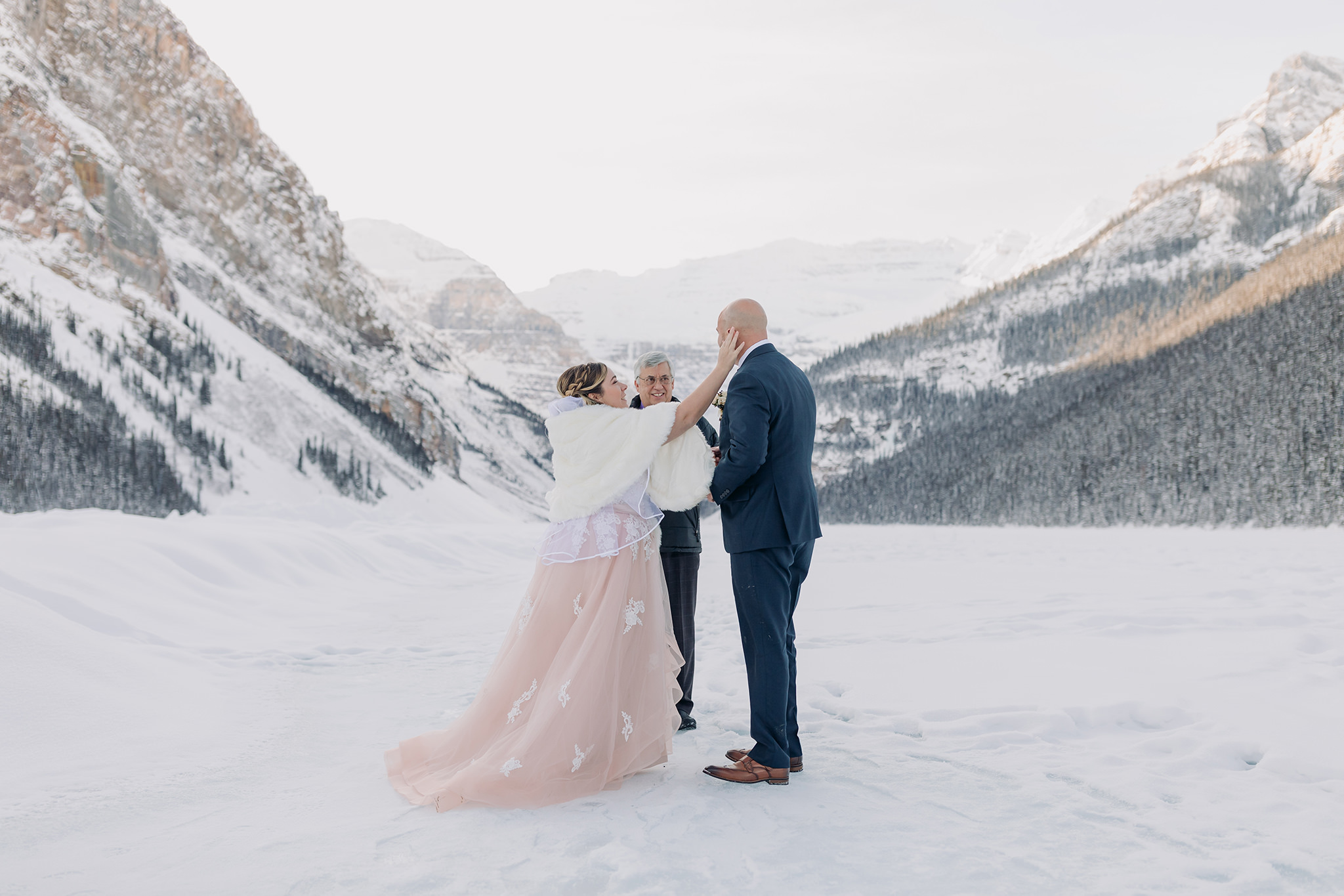 Lake Louise winter elopement ceremony on the frozen Lake Bride in pink wedding dress in winter wonderland Super snowy wedding ceremony photographed by ENV Photography