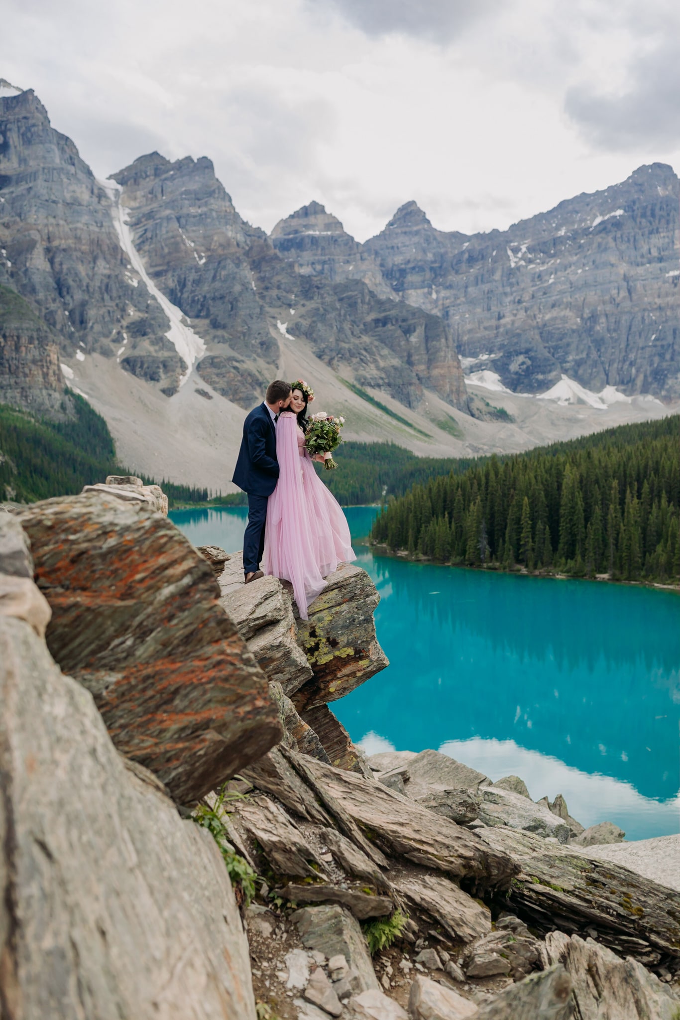 A Guide to Eloping in the Canadian Rockies | Mountain Wedding photographed by ENV Photography | newlyweds elope at Moraine Lake Bride in pink dress, cape & floral crown