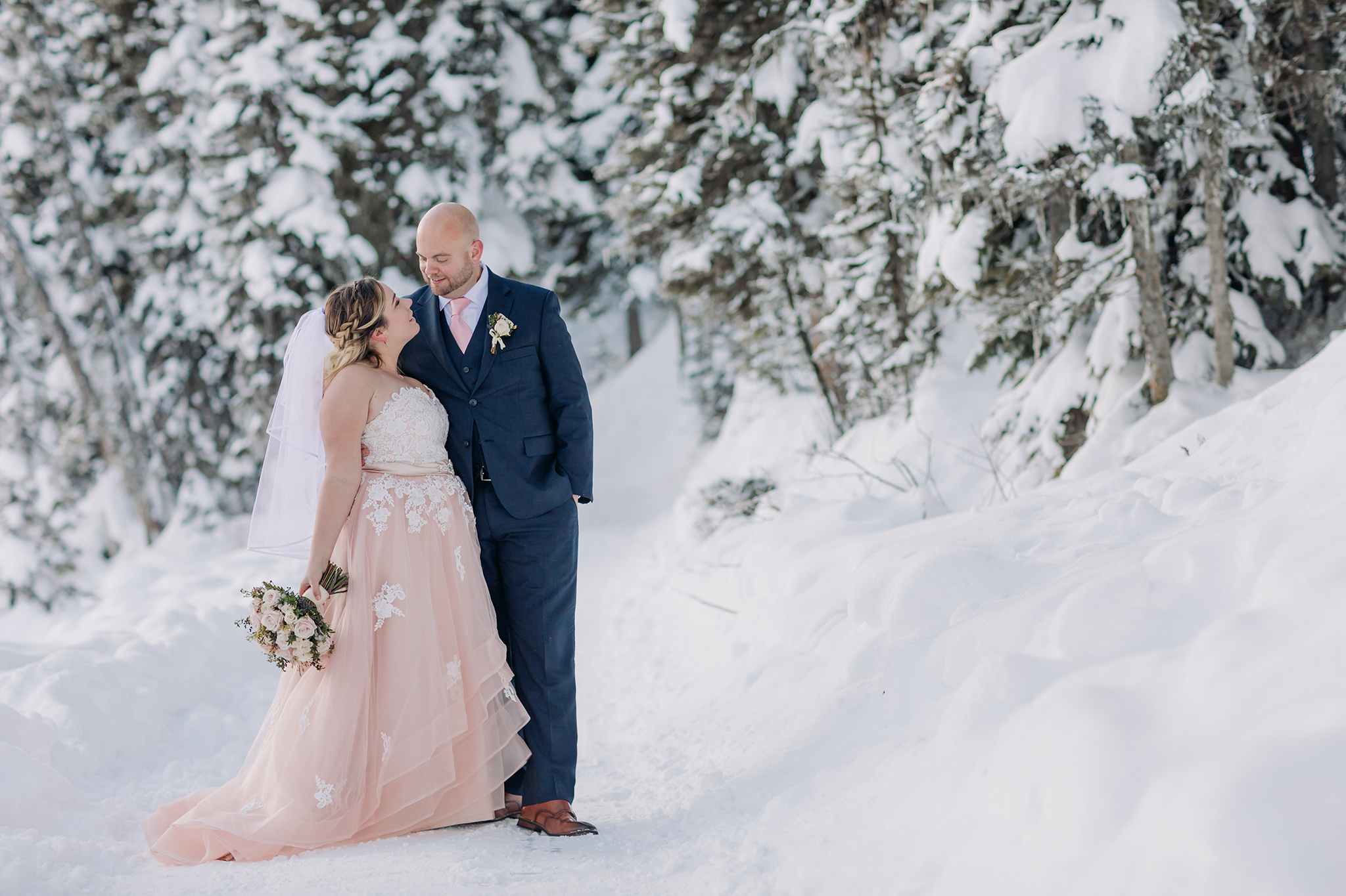 Lake Louise winter elopement on frozen Lake Louise with Bride in pink wedding dress in winter wonderland Super snowy elopement wedding photographed by ENV Photography on Bow Valley Parkway