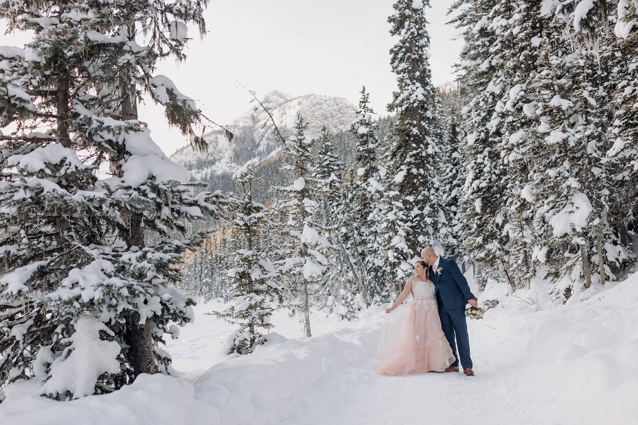 Lake Louise winter elopement on frozen Lake Louise with Bride in pink wedding dress in winter wonderland Super snowy elopement wedding photographed by ENV Photography
