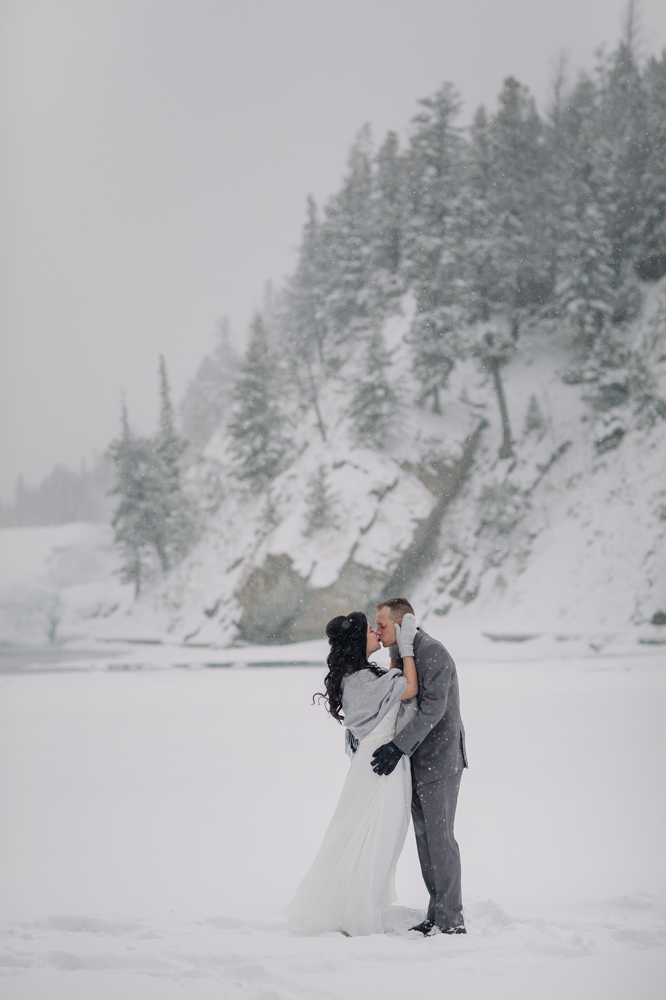 winter wedding portraits at Bow Falls in a snow storm in Banff National Park in the Canadian Rocky Mountains photographed by ENV Photography