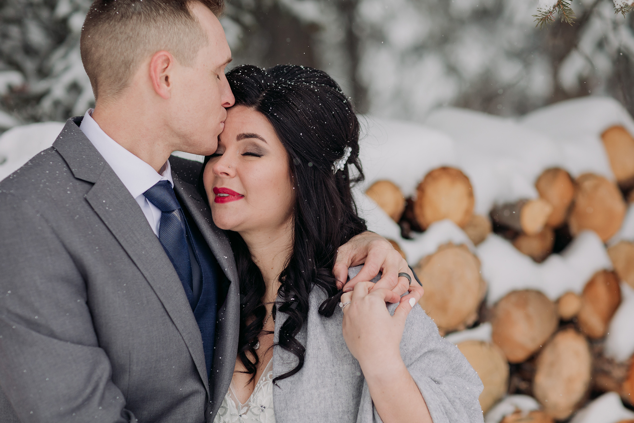 winter wedding portraits at Juniper Hotel woodpile in a snow storm in Banff National Park in the Canadian Rocky Mountains photographed by ENV Photography