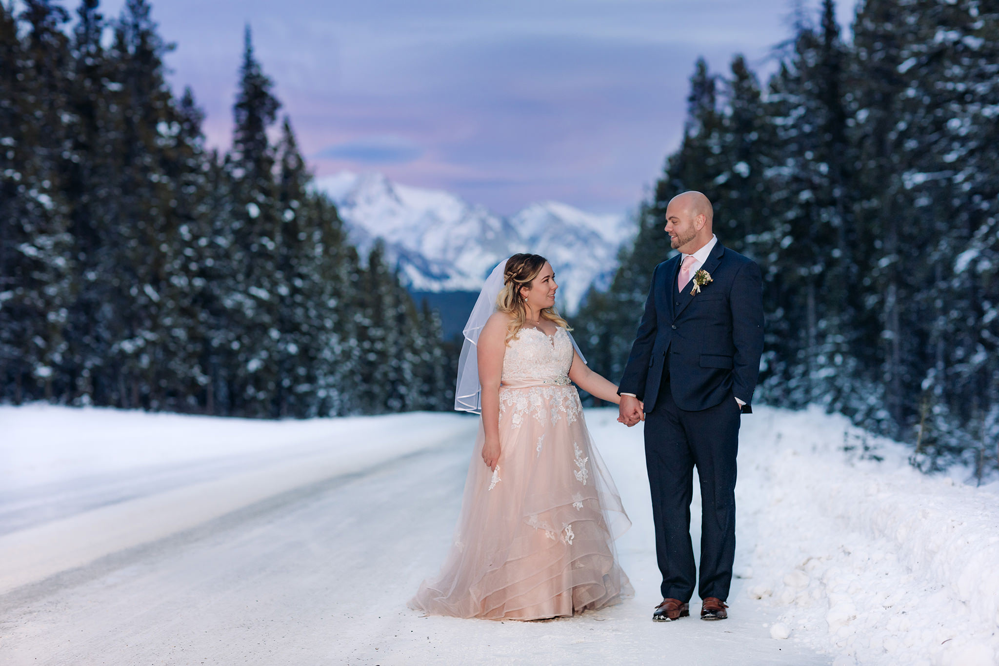 Lake Louise winter elopement on frozen Lake Louise with Bride in pink wedding dress in winter wonderland on the Bow Valley Parkway at sunset in Banff National Park photographed by ENV Photography
