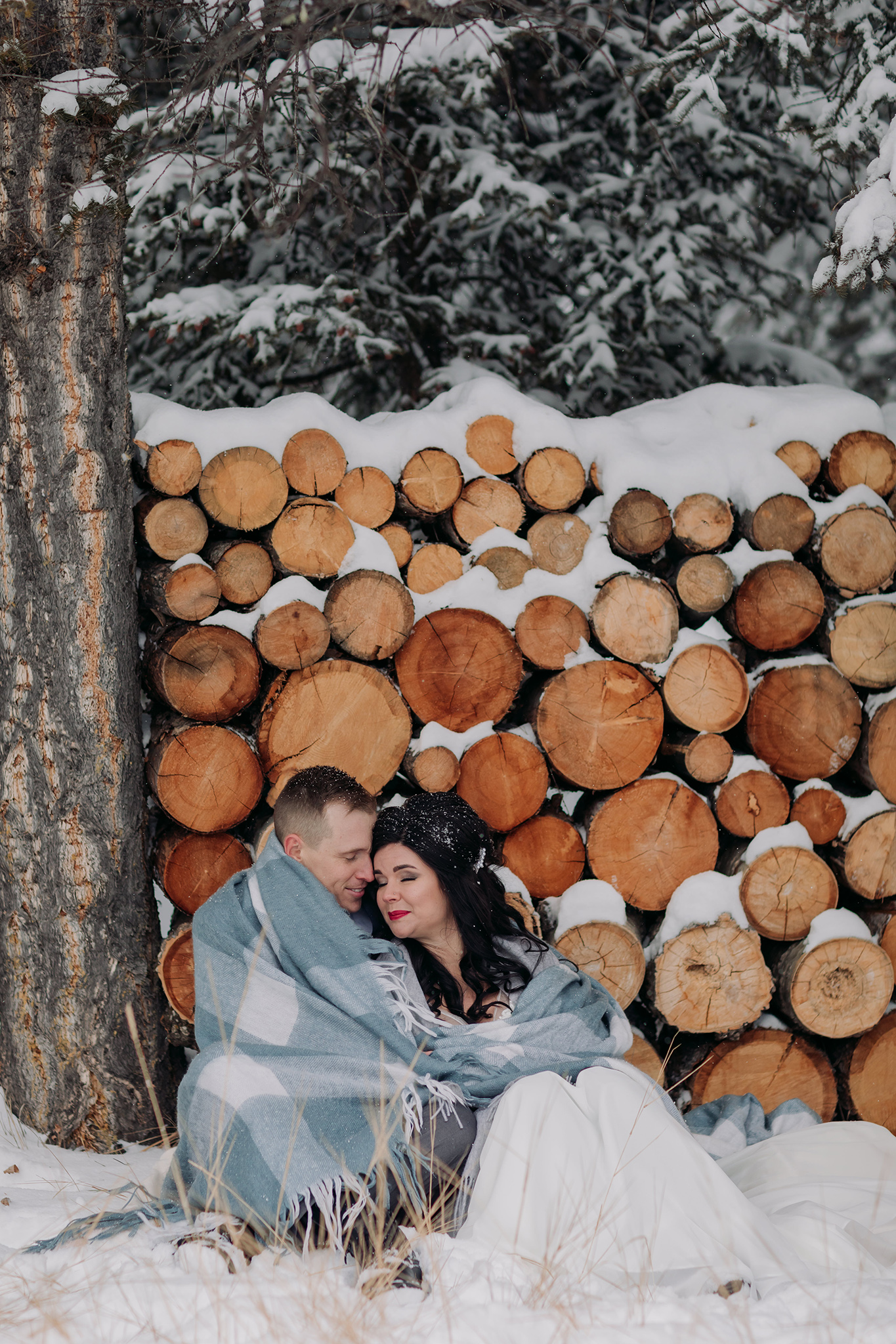 bride groom portraits at Juniper Hotel woodpile in a snow storm in Banff National Park in the Canadian Rocky Mountains photographed by ENV Photography