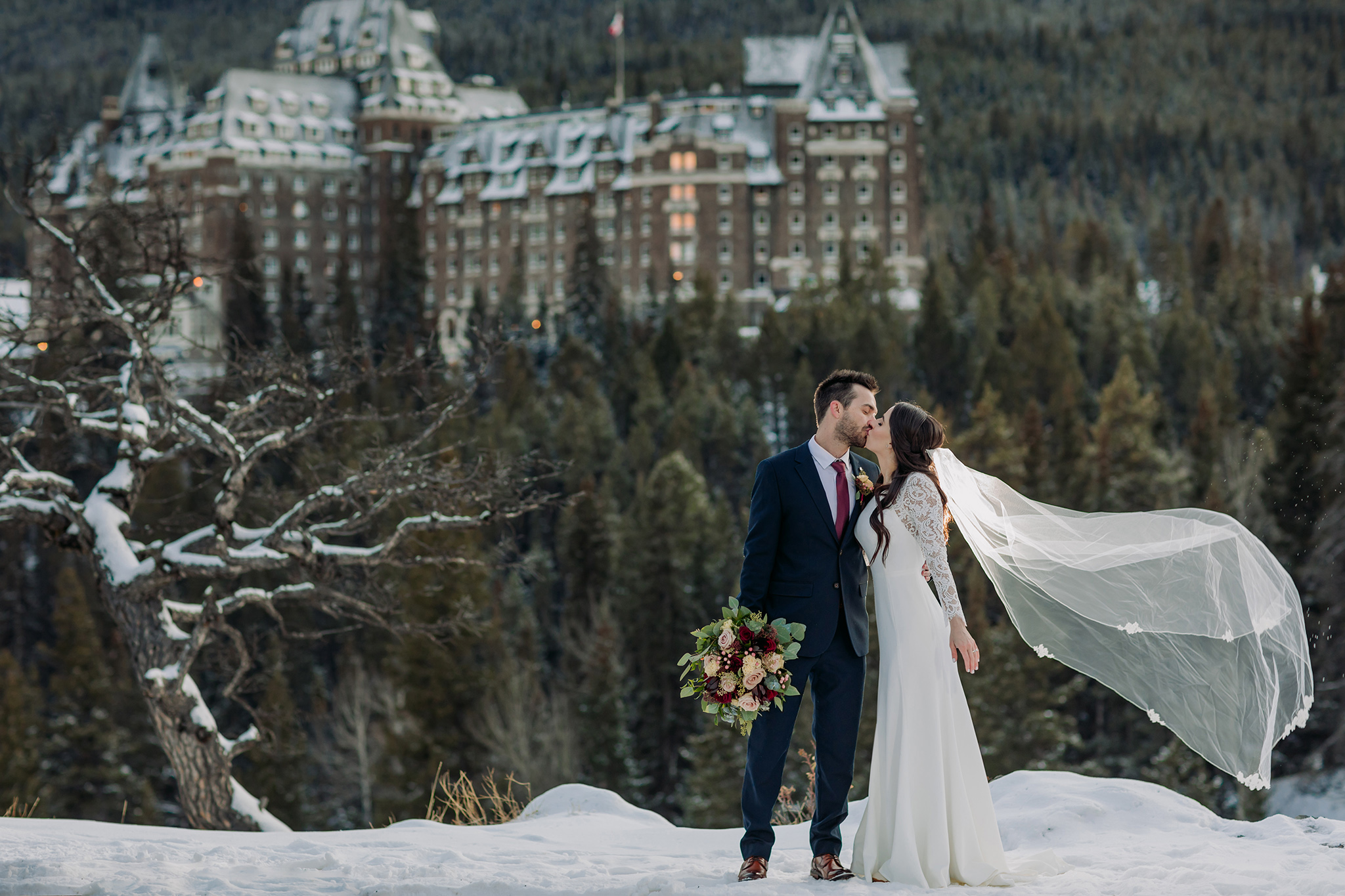A Guide to Eloping in the Canadian Rockies | Mountain Wedding photographed by ENV Photography | Elegant winter wedding at Surprise corner in Banff with the Fairmont Banff Springs hotel in the distance.