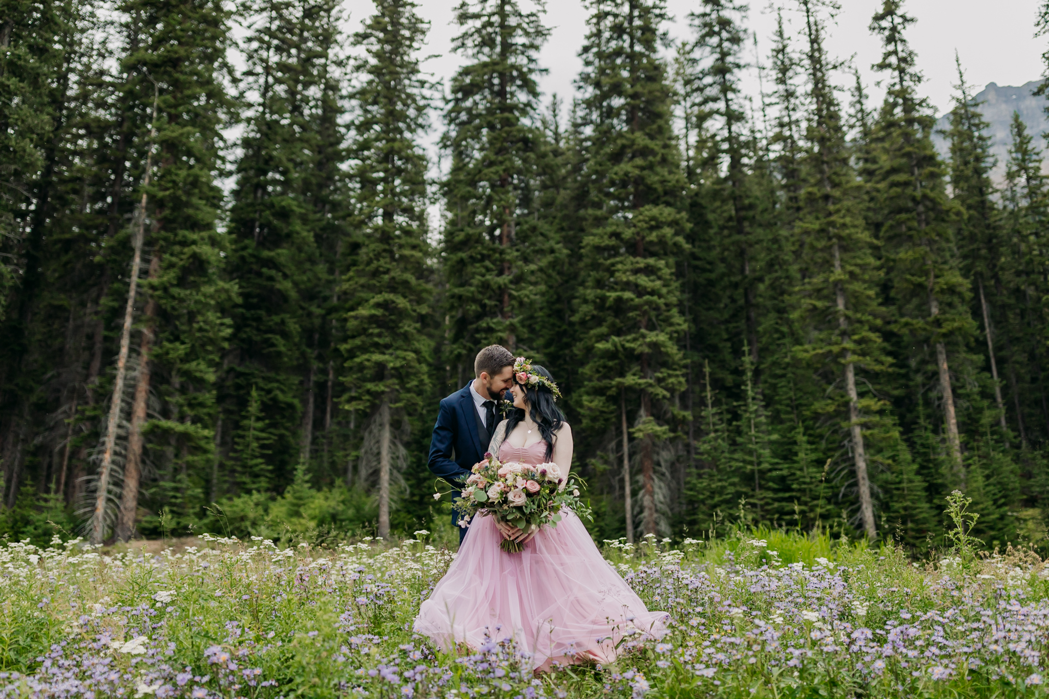 A Guide to Eloping in the Canadian Rockies | Mountain Wedding photographed by ENV Photography | woodland forest wedding at Moraine Lake in the trees. Bride in vintage pink gown & floral crown. Boho mountain wedding.