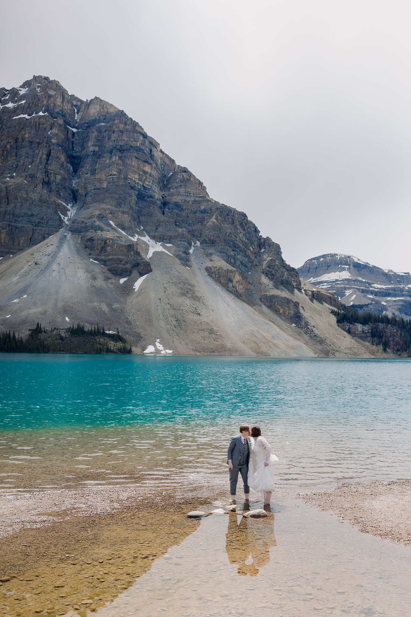 Post-wedding portraits wading in Bow Lake. same-sex wedding. Mountain Wedding portraits photographed by ENV Photography. Gay friendly. LGBTQ friendly wedding & elopement photographer.g portraits on the shores of Bow Lake. same-sex wedding. Mountain Wedding portraits photographed by ENV Photography. Gay friendly. LGBTQ friendly wedding & elopement photographer.