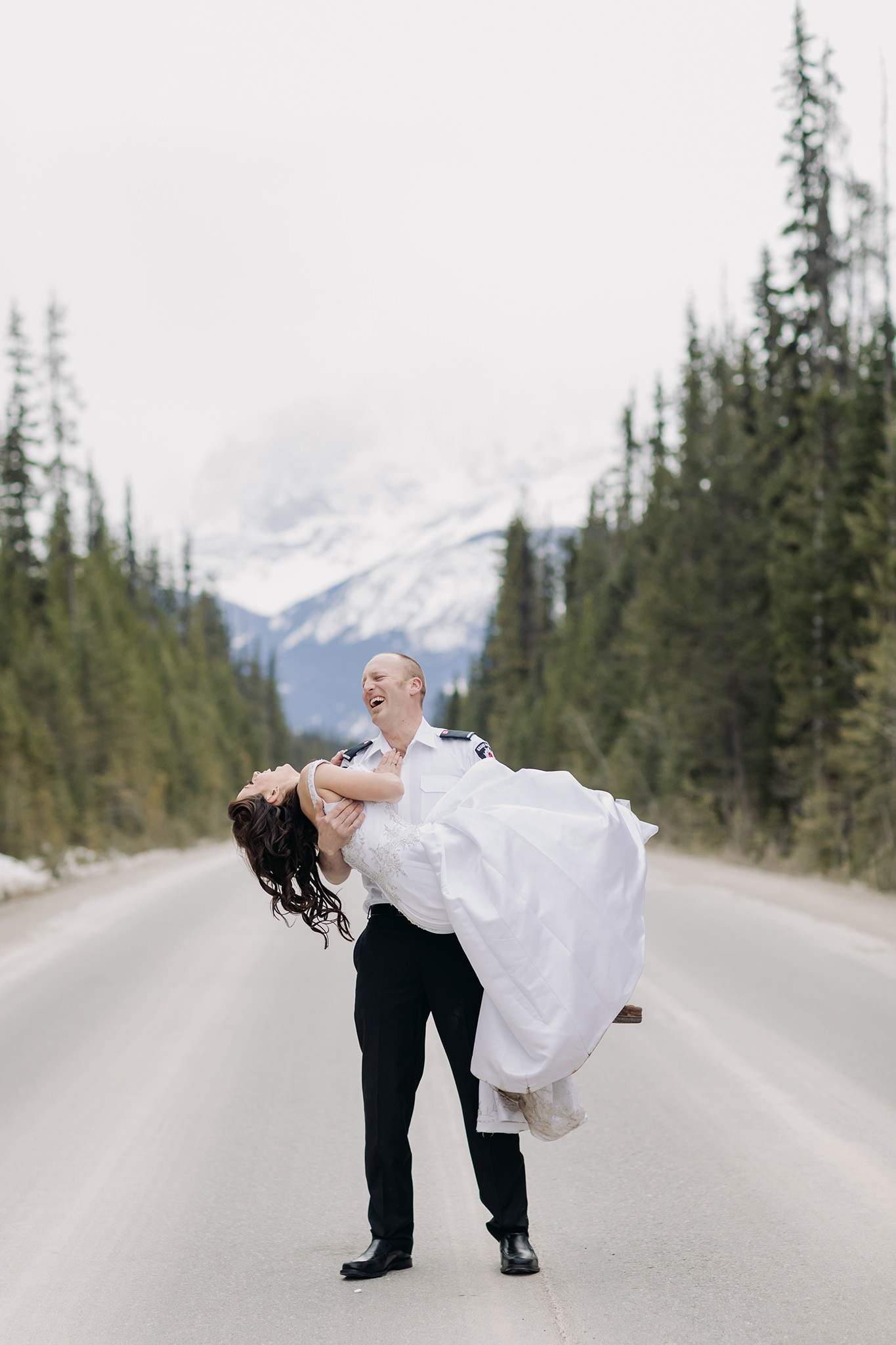 bride swept off her feet laughing in the road to Emerald Lake Lodge for spring mountain elopement