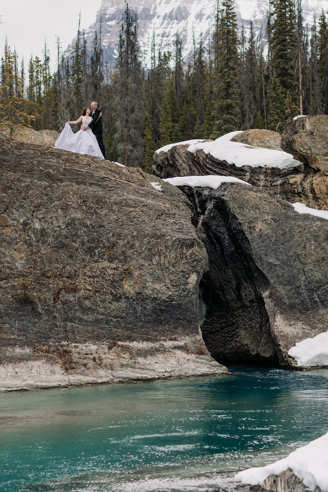 portraits at the natural bridge in yoho national park snow & open river water with incredible blue-green colour