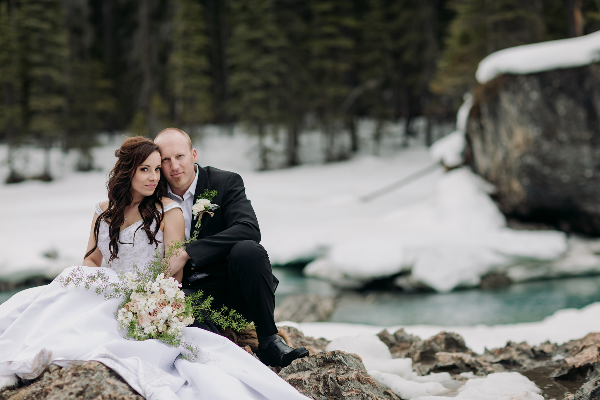 Spring mountain elopement portraits at the natural bridge in yoho national park snow & open river water with incredible blue-green colour