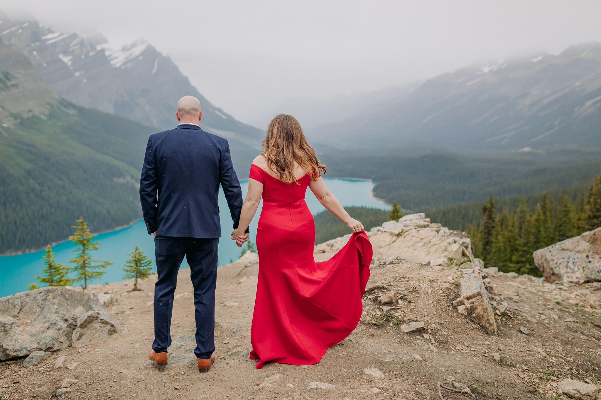 Peyto Lake Formal engagement photos on a cold rainy day in the mountains in Banff National Park. Featuring stunning red evening gown & dramatic blue lake backdrop photographed by ENV Photography