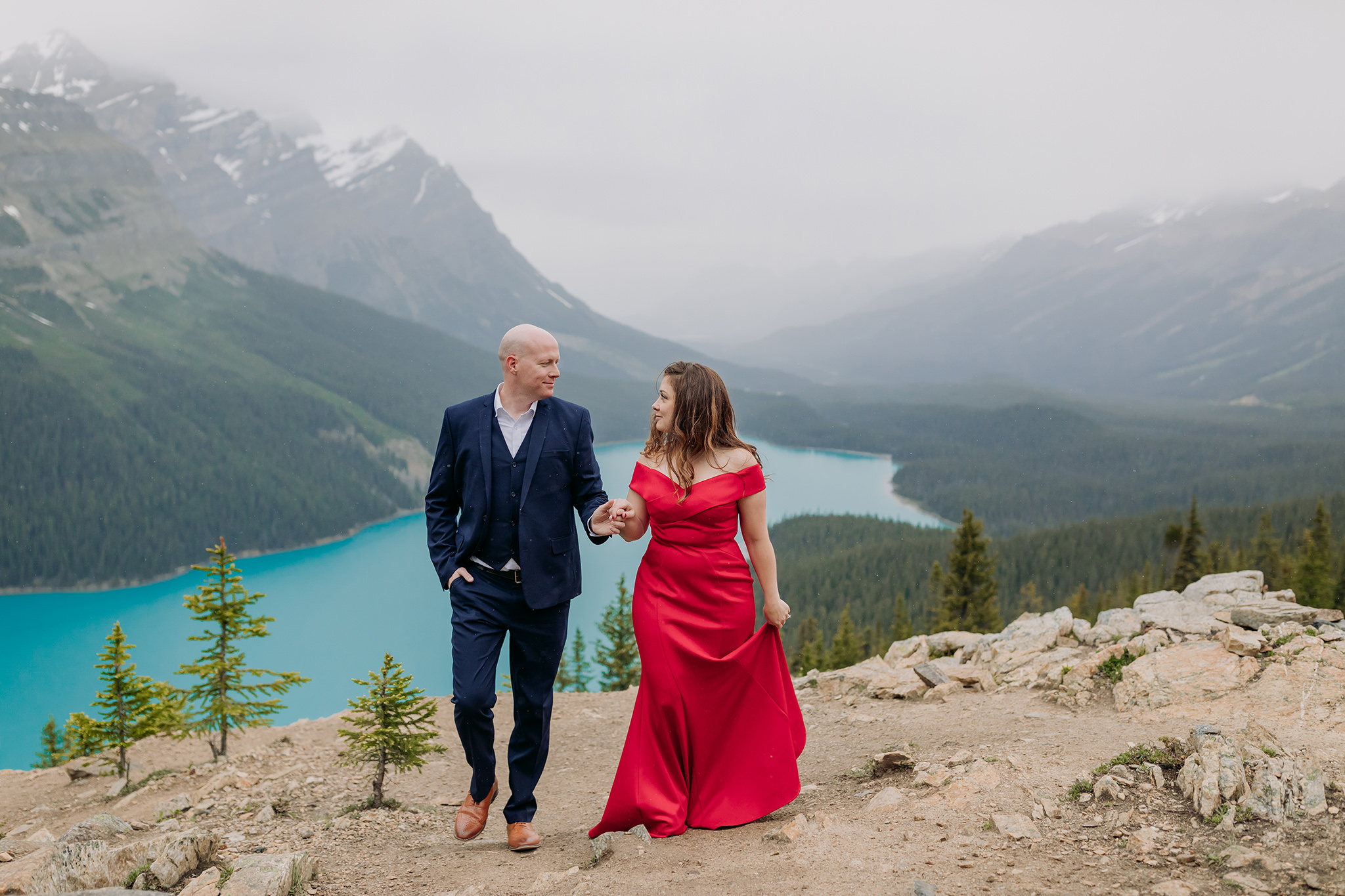 Peyto Lake Formal engagement photos on a cold rainy day in the mountains in Banff National Park. Featuring stunning red evening gown & dramatic blue lake backdrop photographed by ENV Photography