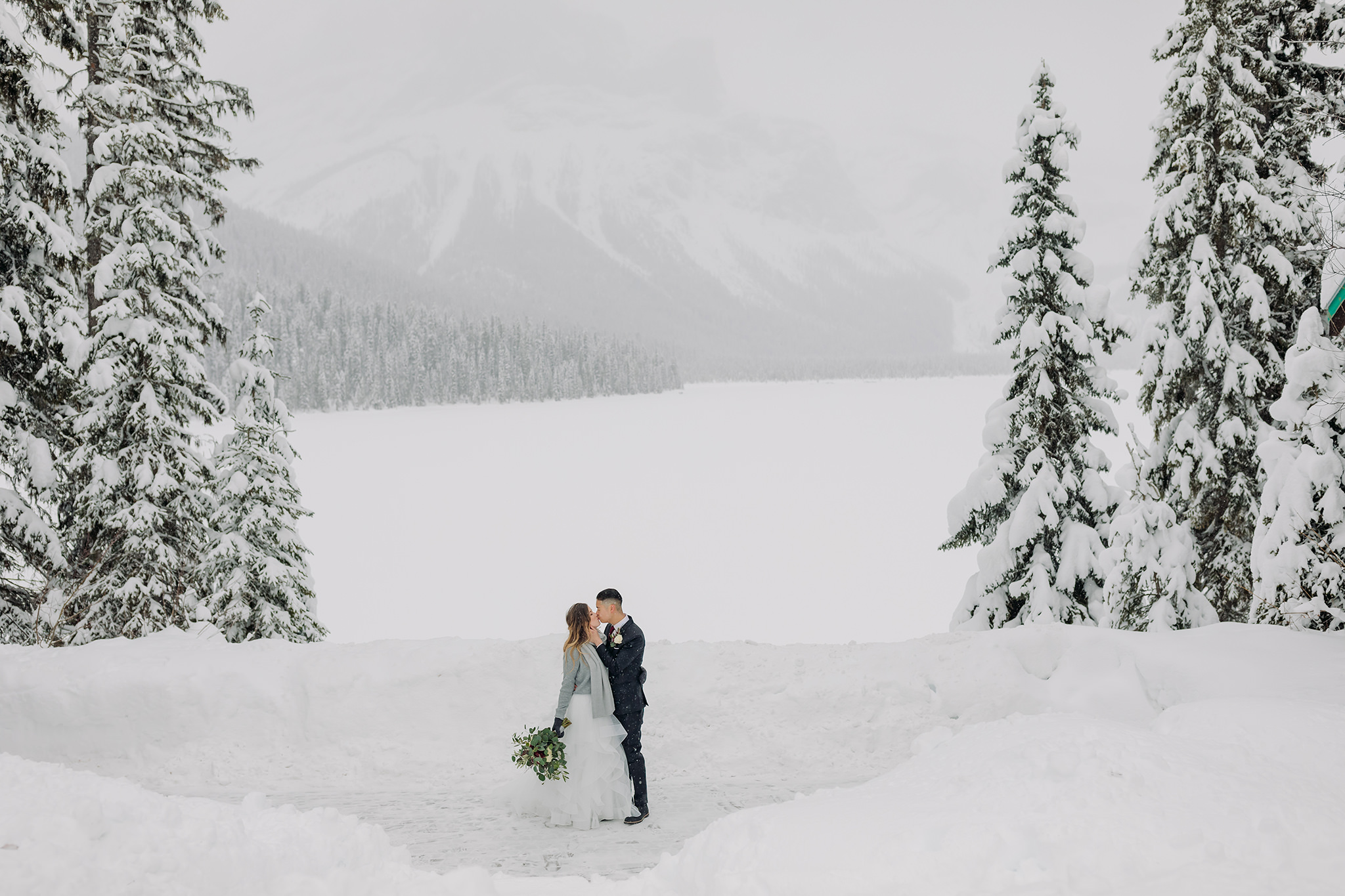 Snowy winter elopement at Emerald Lake Lodge in Yoho National Park. Outdoor winter wedding ceremony at the Viewpoint overlooking mountains & forest.