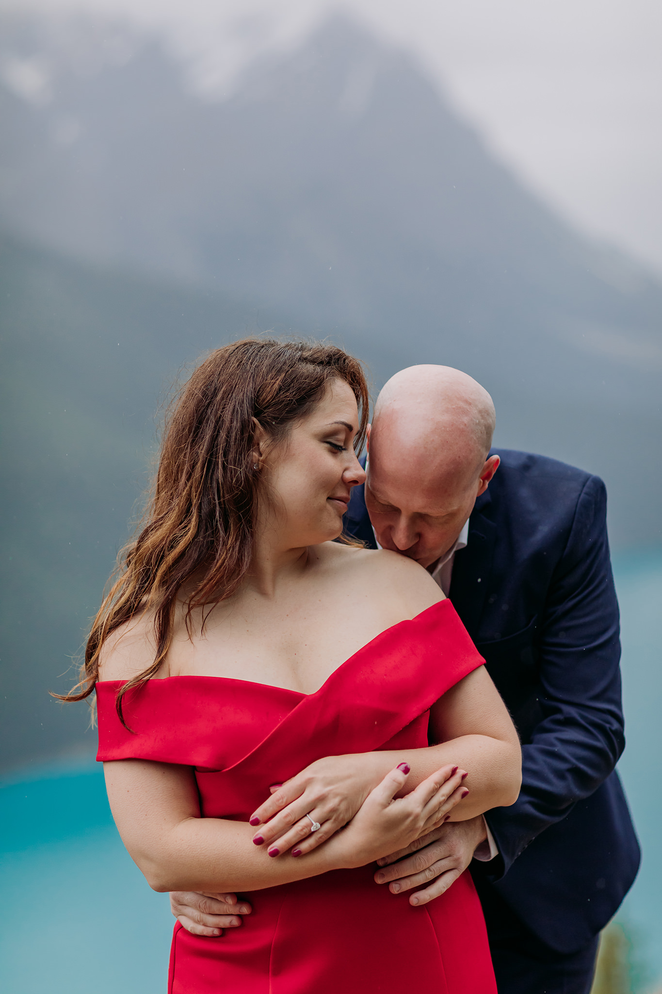 Bow Summit on Icefields Parkway couples vacation photos on a cold rainy day in the mountains in Banff National Park. Featuring stunning red evening gown & dramatic mountain views photographed by ENV Photography