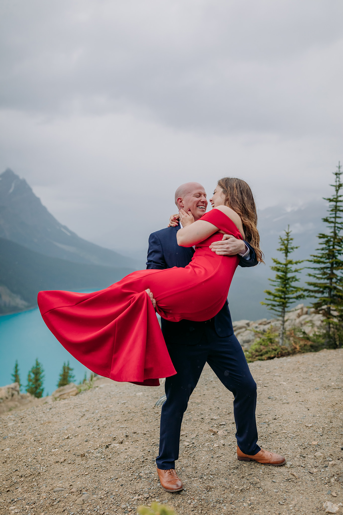 Bow Summit on Icefields Parkway couples vacation photos on a cold rainy day in the mountains in Banff National Park. Featuring stunning red evening gown & dramatic mountain views photographed by ENV Photography