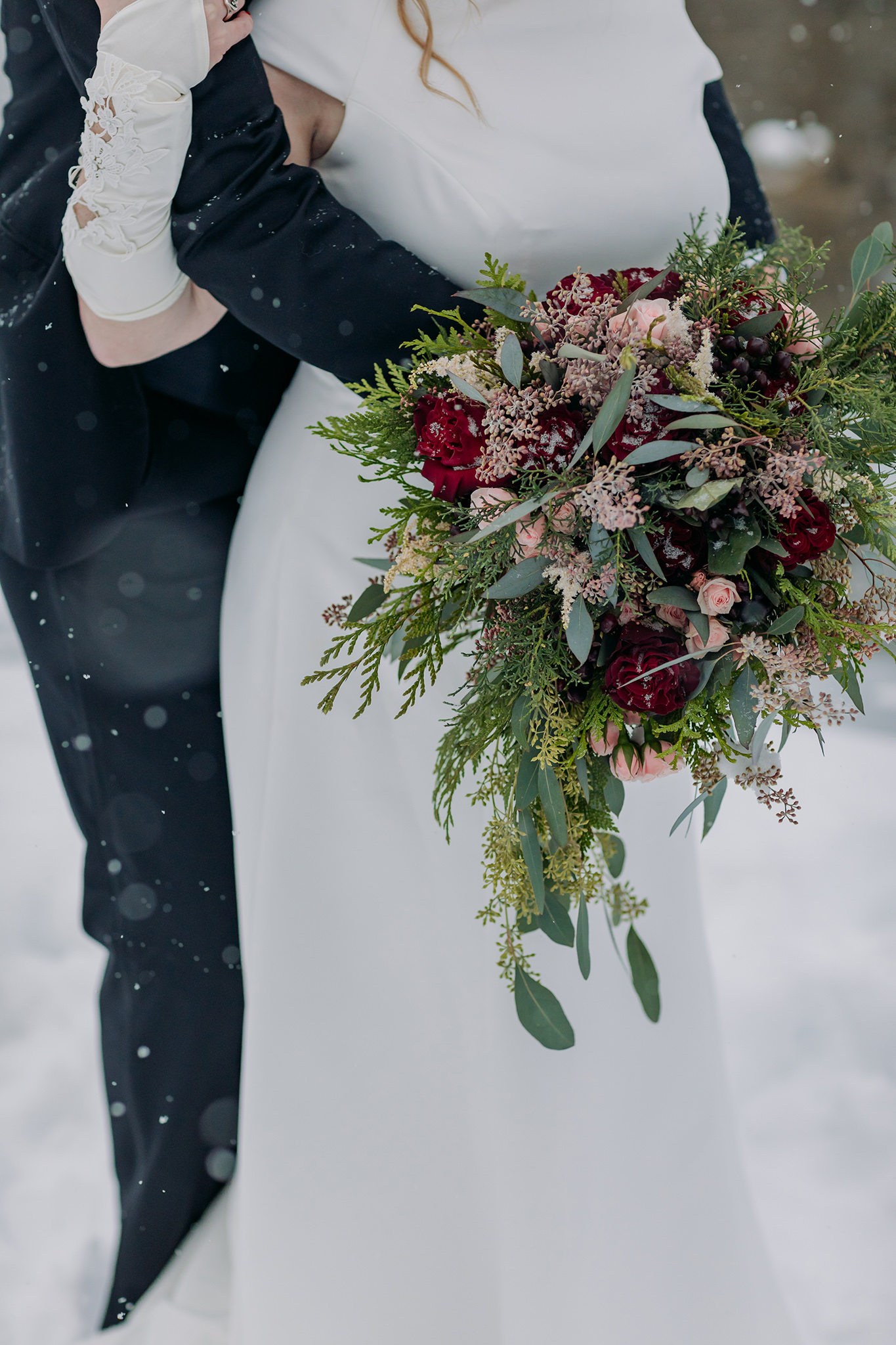 emerald lake lodge winter wedding bride & groom holding wild unstructured winter wedding bouquet in blush, burgundy & green