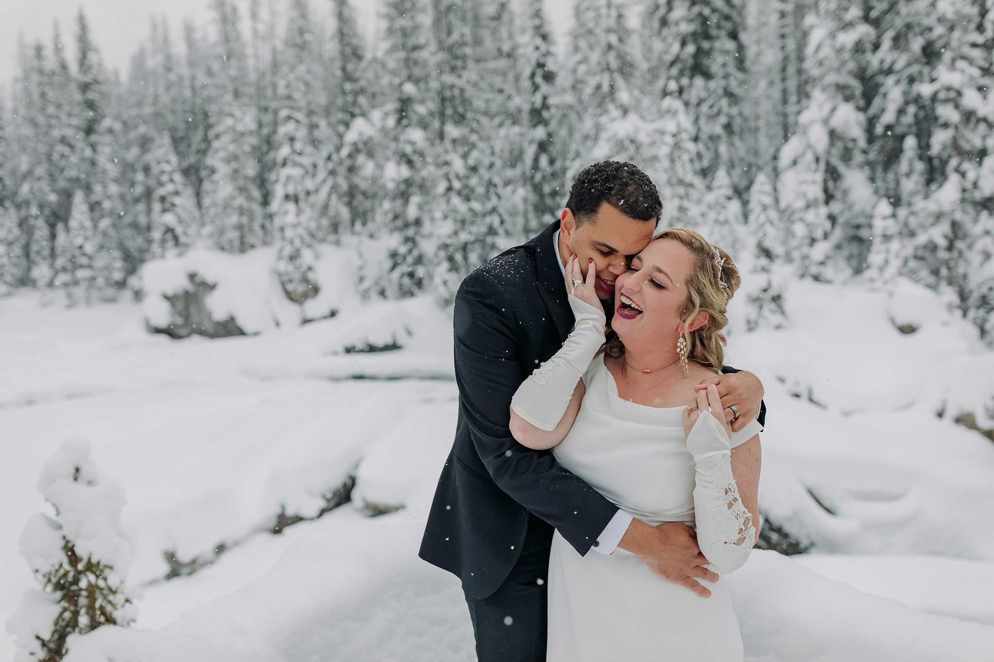 Emerald Lake Lodge outdoor winter wedding bride & groom portraits in a real life snow globe at the natural bridge in Yoho National Park photographed by mountain elopement photographer ENV Photography