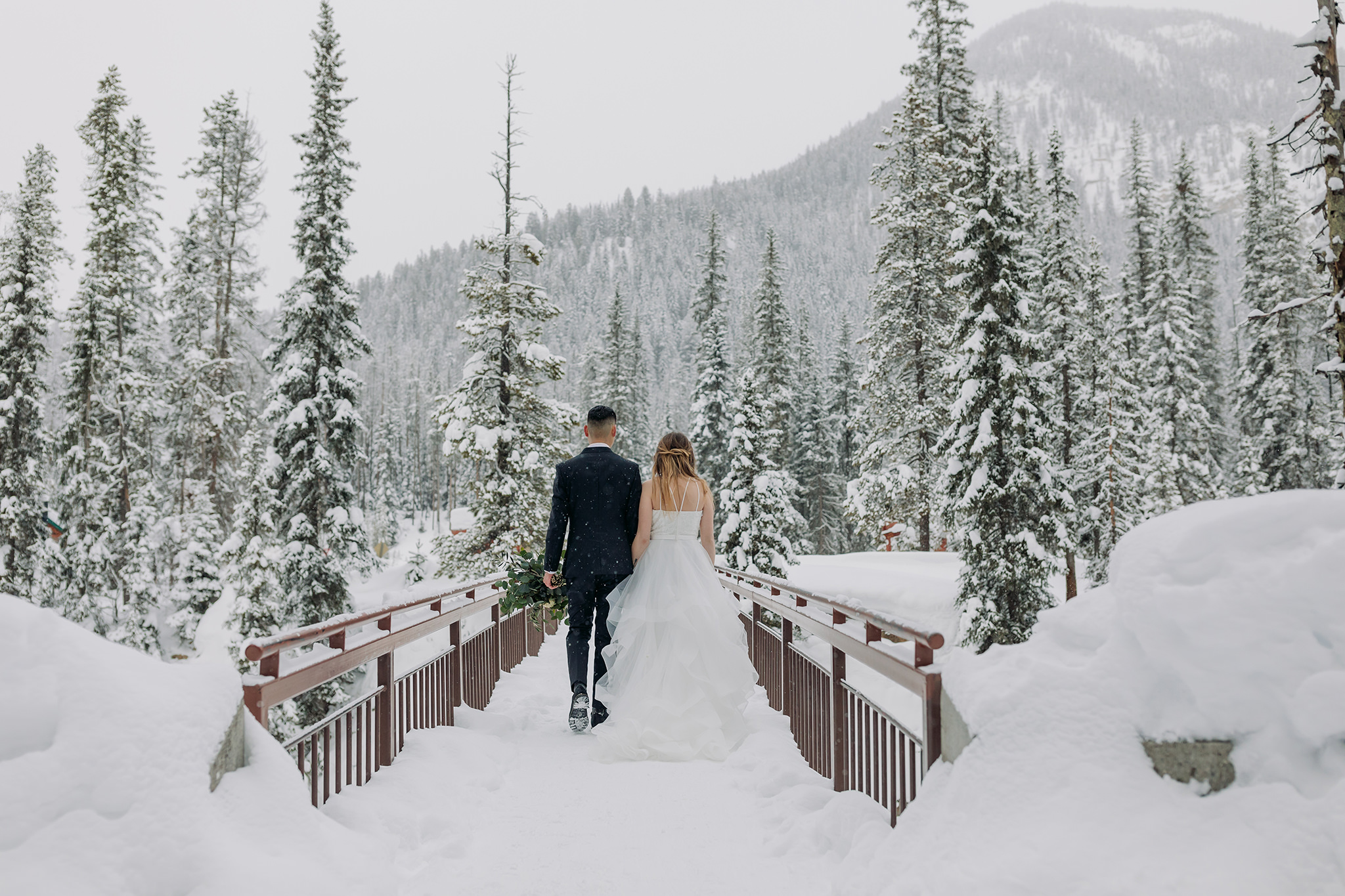 Snowy winter elopement portraits at the natural bridge in Yoho National Park. Mountain wedding in a winter wonderland. 