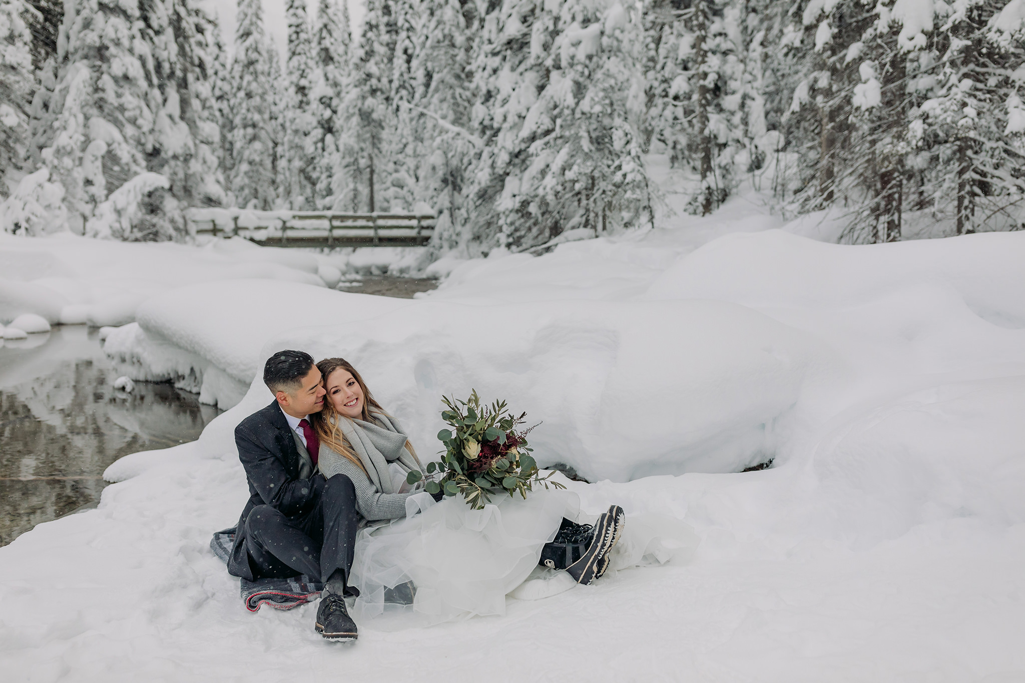 Snowy winter elopement portraits at Emerald Lake Lodge in Yoho National Park. Mountain wedding in a winter wonderland. Bride in a cozy sweater & matching scarf to keep warm. What to wear for a winter wedding. 