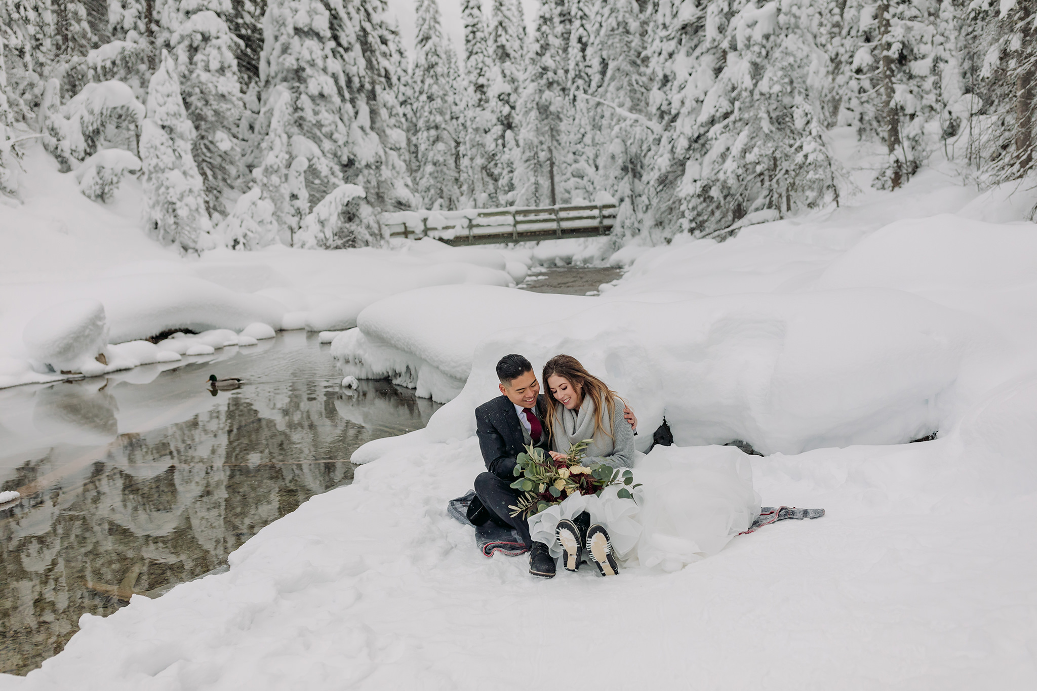 Snowy winter elopement portraits at Emerald Lake Lodge in Yoho National Park. Mountain wedding in a winter wonderland. Bride in a cozy sweater & matching scarf to keep warm. What to wear for a winter wedding. 