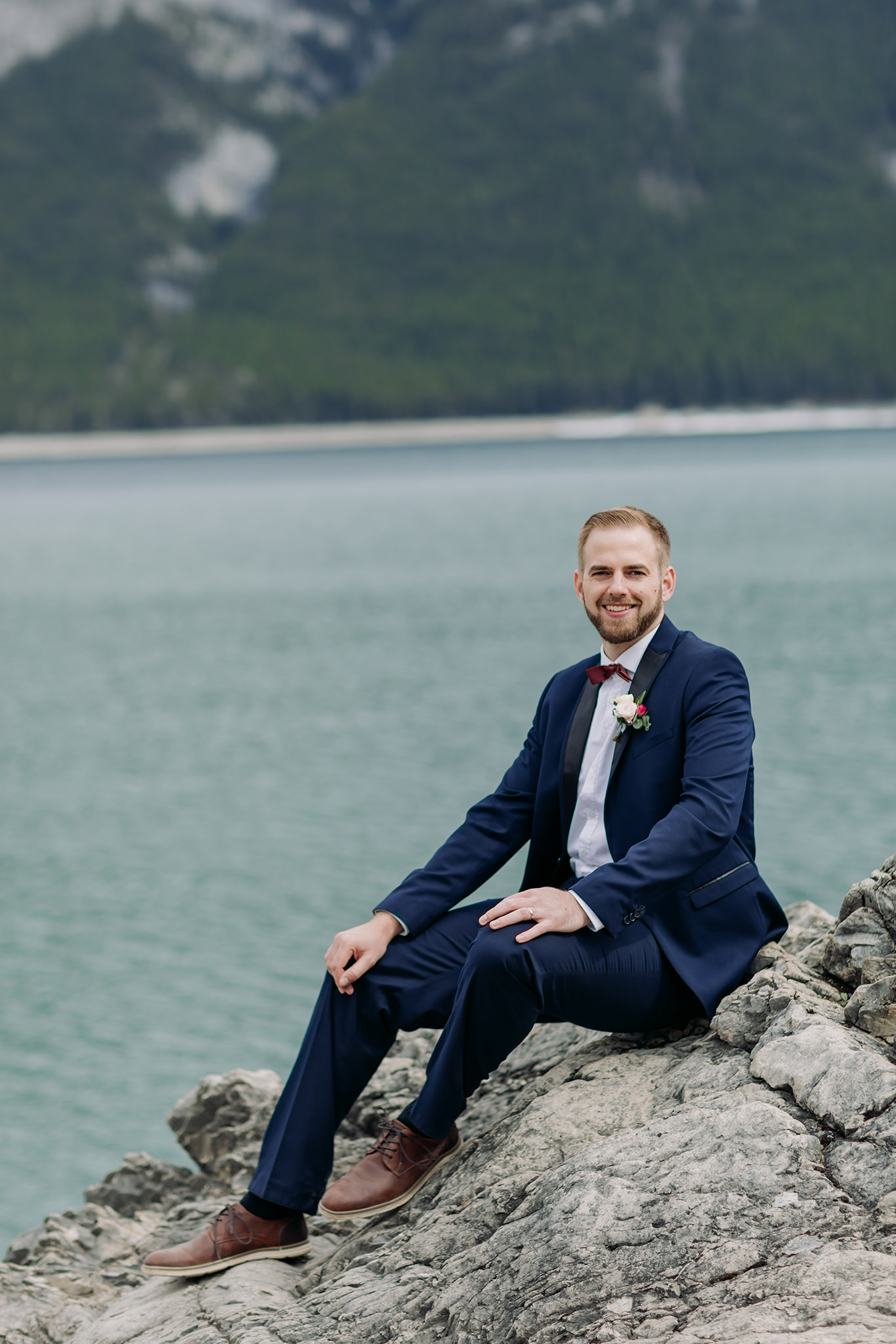 groom posing alone at Lake Minnewanka in Banff