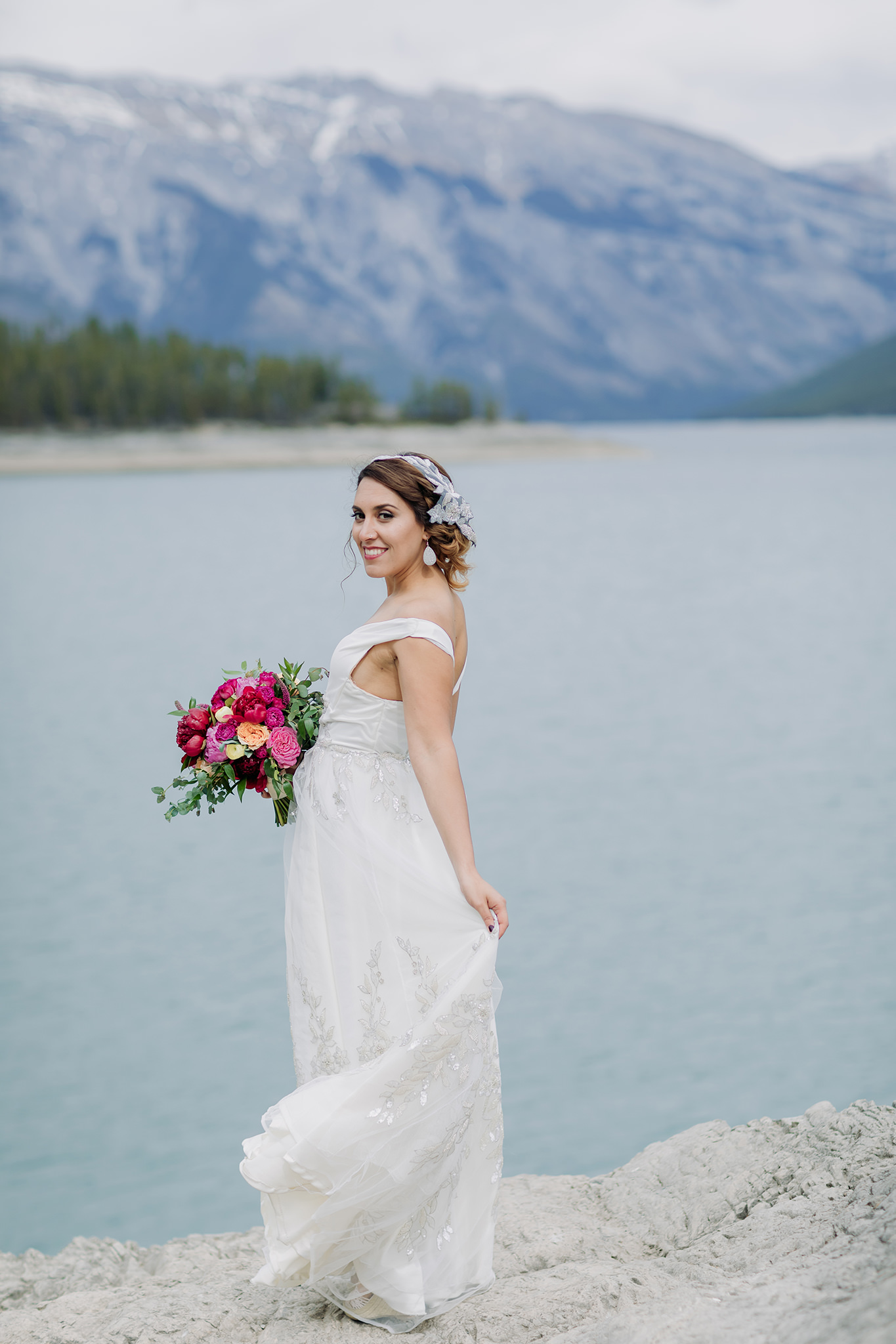 bride posing alone at Lake Minnewanka in Banff