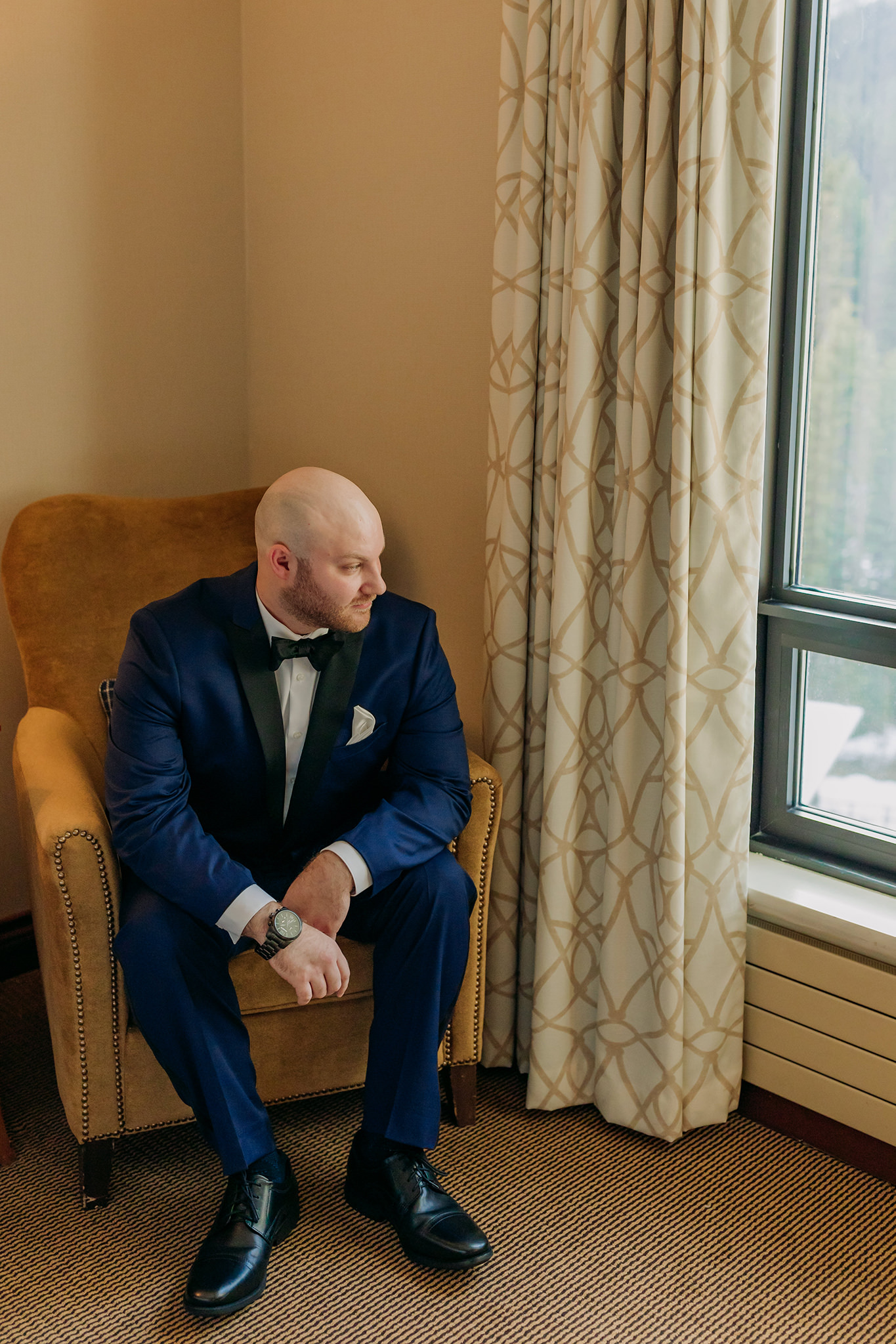 Groom getting ready for his outdoor winter wedding in a suite at the Fairmont Chateau Lake Louise in te Canadian Rocky Mountains