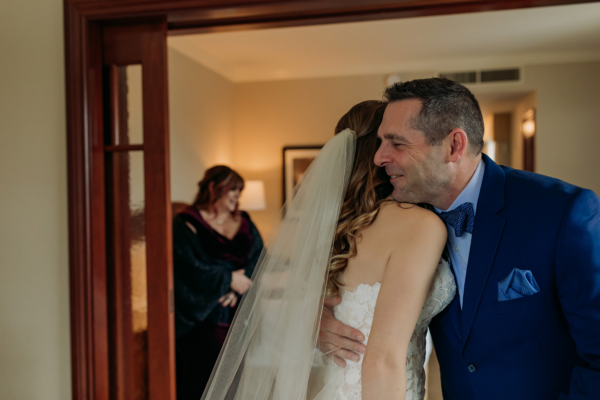 Bride getting ready for her outdoor winter wedding in a suite at the Fairmont Chateau Lake Louise in the Canadian Rocky Mountains first look with dad