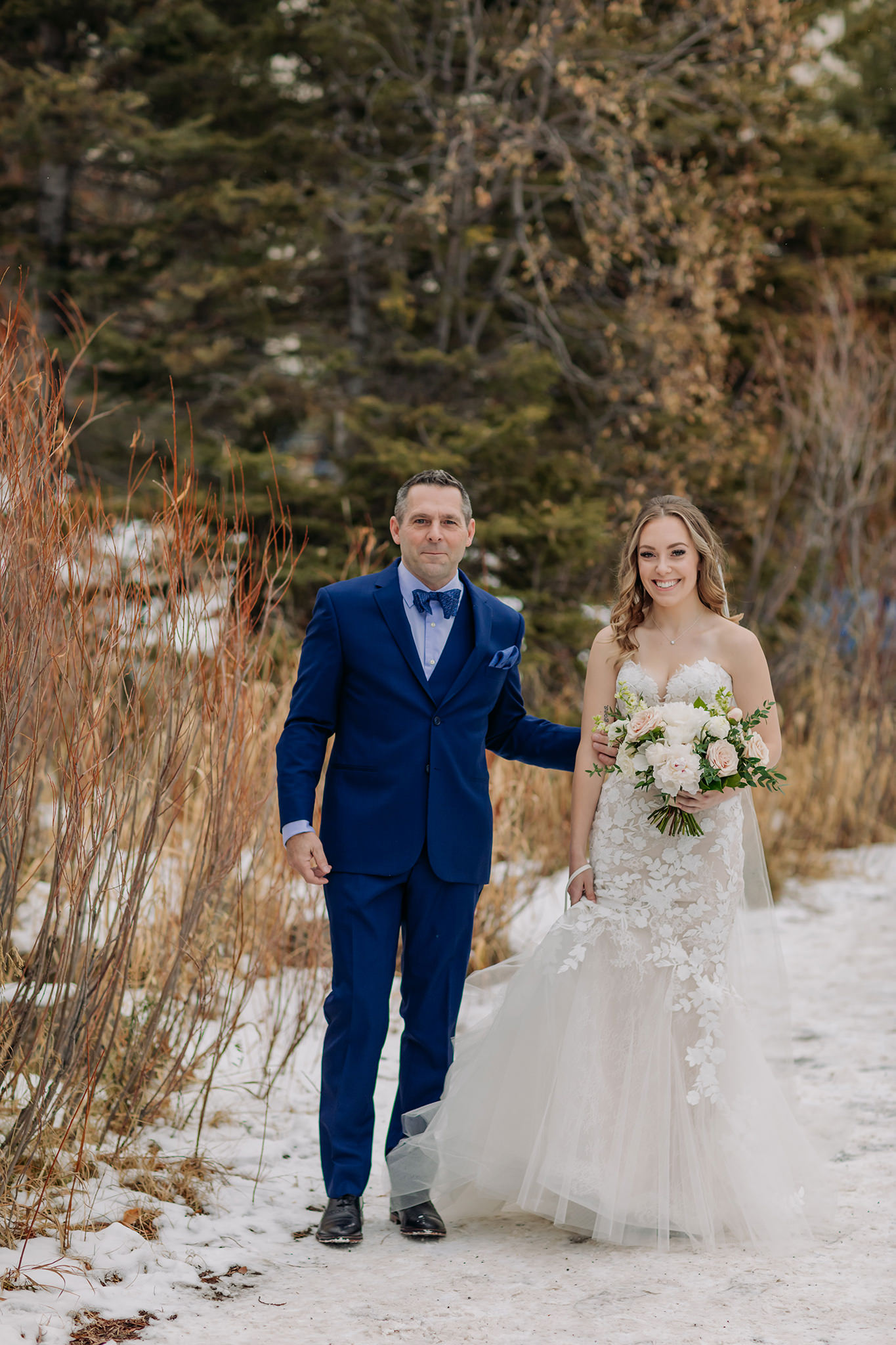 Bride & father walking the snowy paths to the lakeside ceremoyn at Lake Louise in the winter