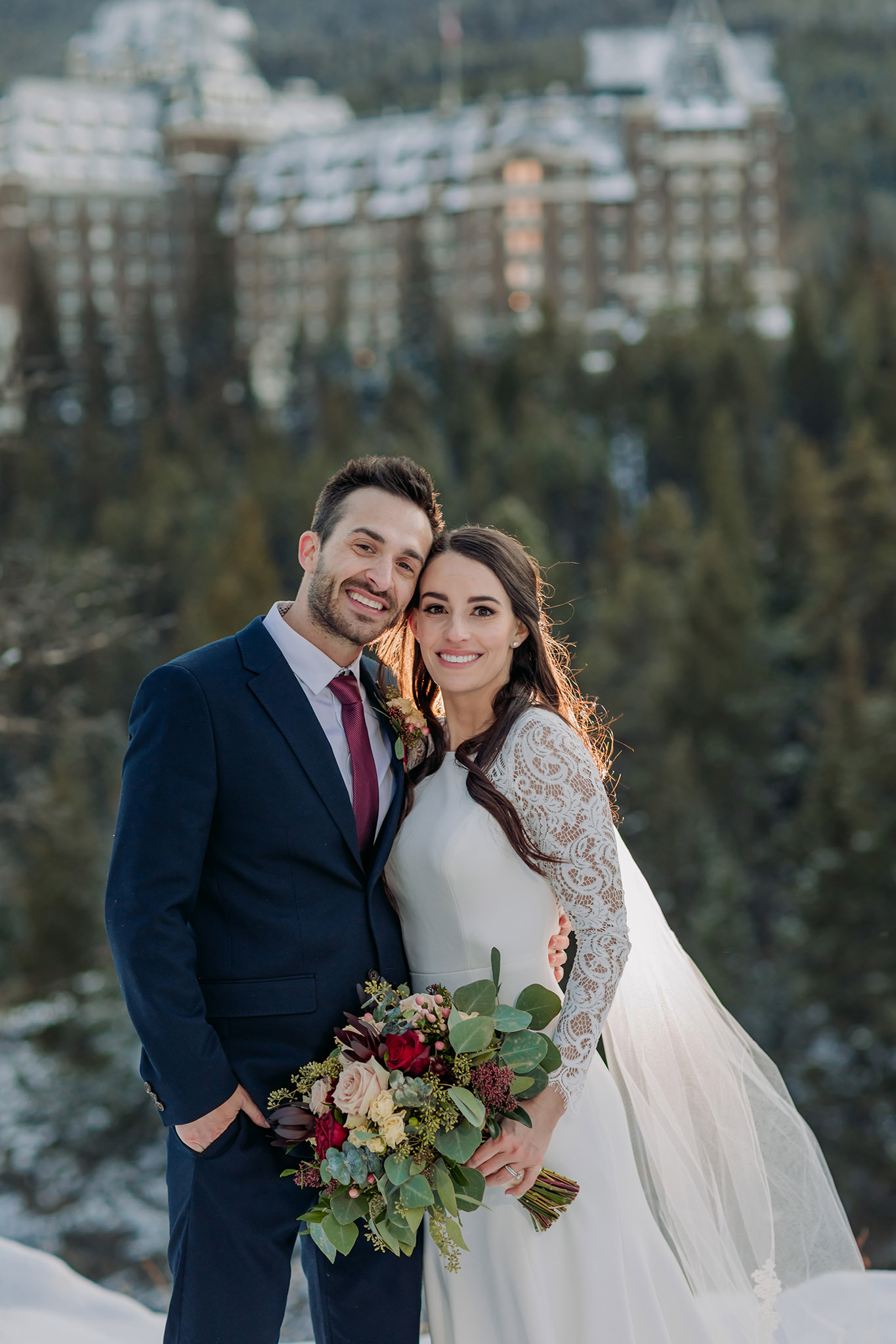 Banff winter wedding portraits at Surprise Corner in the mountains with Fairmont Banff Springs in the distance