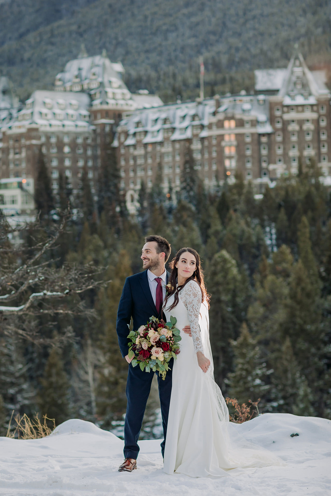Banff winter wedding portraits at Surprise Corner in the mountains with Fairmont Banff Springs in the distance
