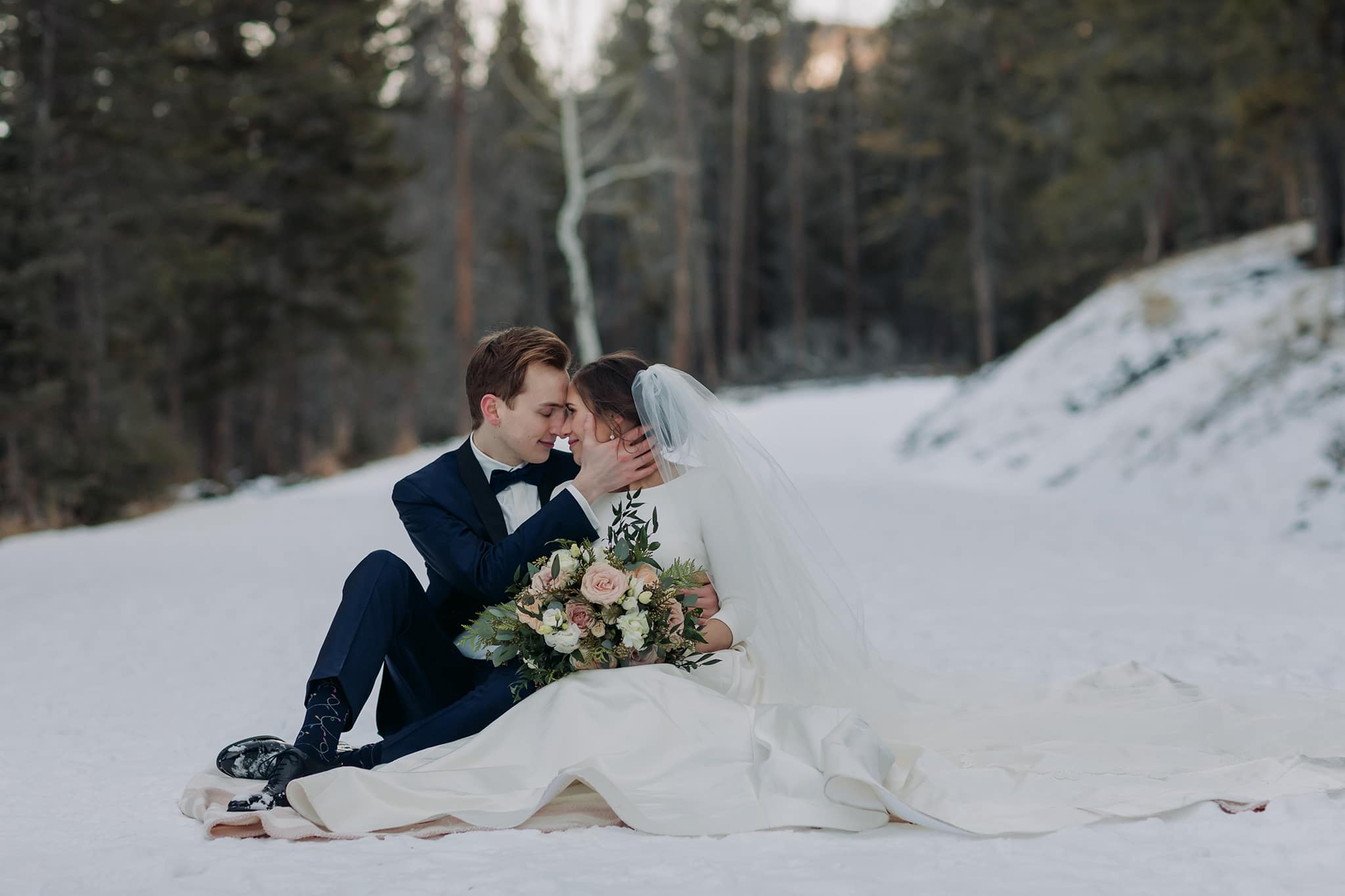 bride groom sitting in snow-covered road on wedding day in Banff National Park winter wedding
