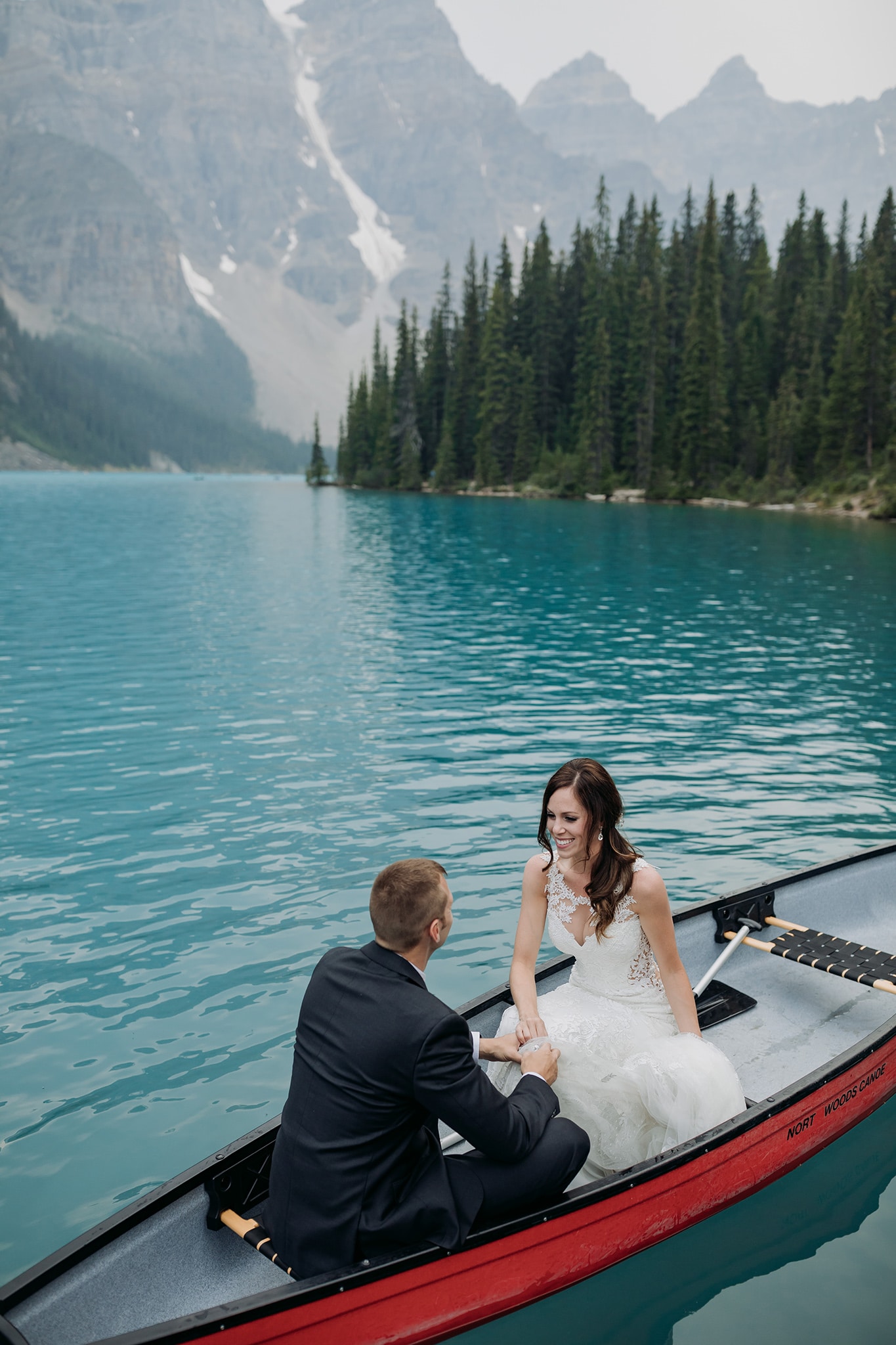A Guide to Eloping in the Canadian Rockies | Mountain Wedding photographed by ENV Photography | bride & groom in red canoe on Moraine Lake